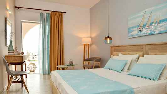 Udsigt over et hotelværelse med en seng, skrivebord og stole, dekoreret med blå og gule farver. (AI-genereret tekst)