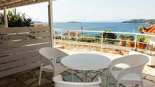 Udendørsområde med hvide plastmøbler og udsigt over havet. (AI-genereret tekst)