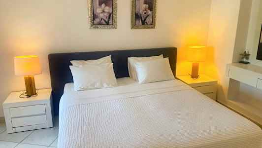 Et soveværelse med en dobbeltseng, to natborde med lamper og to billeder over sengen. (AI-genereret tekst)