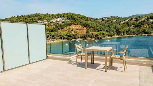 Udsigt fra en terrasse over havet med en stol og et bord. (AI-genereret tekst)