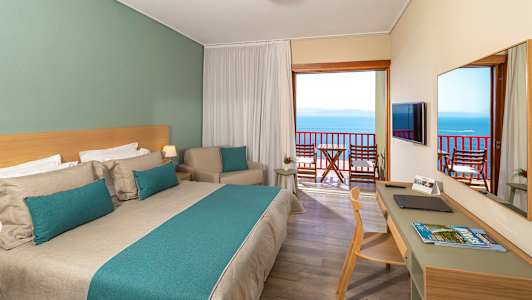 Hotelværelse med dobbeltseng og balkon med havudsigt. (AI-genereret tekst)