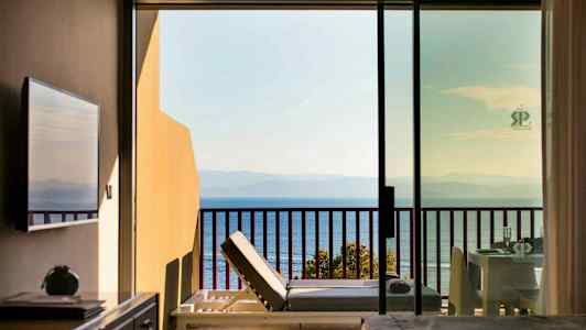 Udsigt fra hotelværelse med balkon mod havet. (AI-genereret tekst)