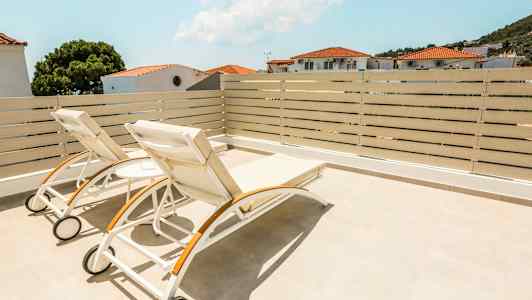 To liggestole på en terrasse med udsigt over huse og træer. (AI-genereret tekst)