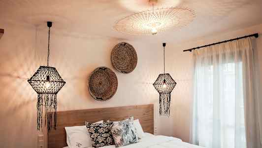 Et soveværelse med dekorative loftlamper, en seng med puder og vægdekorationer. (AI-genereret tekst)