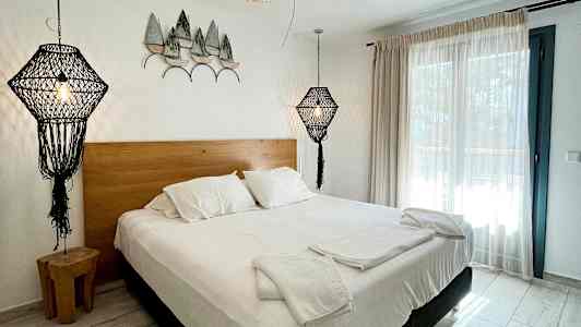 Soveværelse med dobbeltseng, hvidt sengetøj og dekorative lamper i moderne design. (AI-genereret tekst)