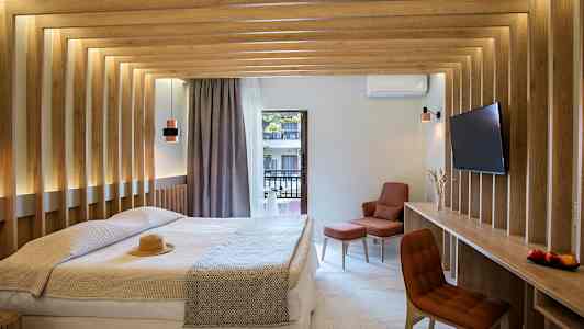 Et moderne hotelværelse med en dobbeltseng, træpaneler på væggene og udsigt til en altan. Værelset har et fjernsyn og en komfortabel siddeplads. (AI-genereret tekst)