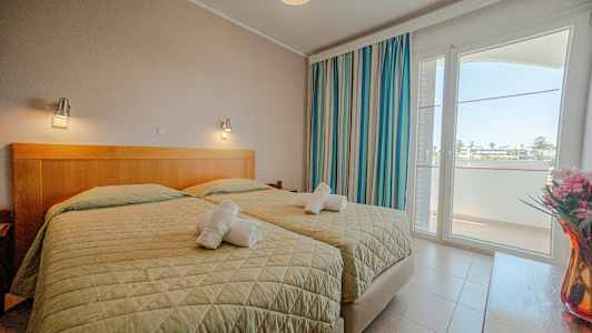 Et hotelværelse med to enkeltsenge, vindue og dekorationer. (AI-genereret tekst)