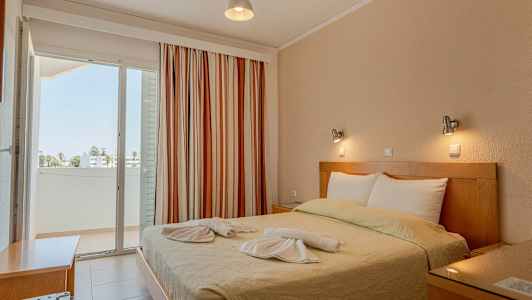 Et soveværelse med en dobbeltseng, dekoreret med håndklæder, og en altan med udsigt. (AI-genereret tekst)