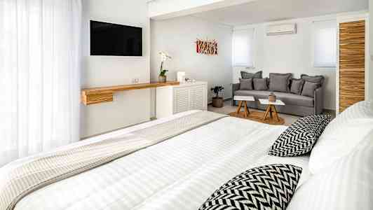 Et lyst, moderne hotelværelse med seng, sofa og TV. (AI-genereret tekst)