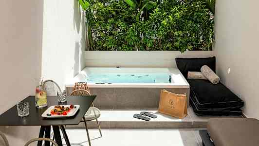 Et udendørsområde med et spabad, liggestole og et bord med drikkevarer og snacks. (AI-genereret tekst)