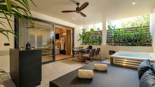 Privat terrasse med spabad, siddeområde og solseng. (AI-genereret tekst)