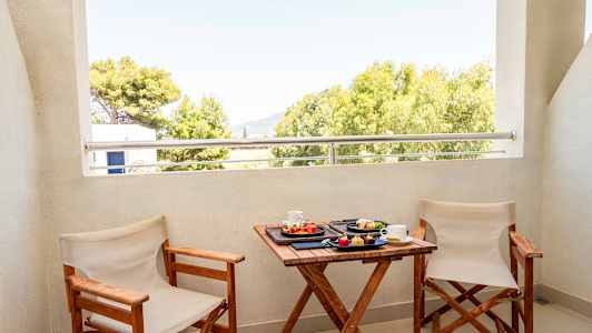 To stole og et bord med morgenmad serveret på en altan med udsigt over træer. (AI-genereret tekst)