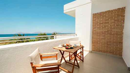 Altan med træbord og to stole, havudsigt i baggrunden. (AI-genereret tekst)