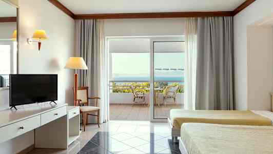 Interiør af et hotelværelse med to senge, skrivebord og en terrasse med udsigt til havet. (AI-genereret tekst)