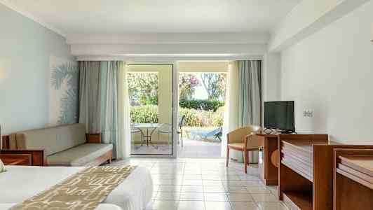 Et hotelværelse med en dobbeltseng, sofa møbler, TV og en terrasse med udsigt over haven. (AI-genereret tekst)