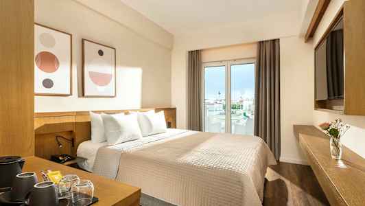 Et hotelværelse med en dobbeltseng, moderne indretning og vinduer med udsigt til byen. (AI-genereret tekst)