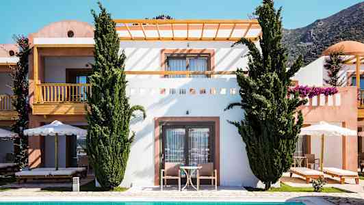 Et billede af en bygning med terrasse og balkon, omgivet af grønne træer og med en pool i forgrunden. (AI-genereret tekst)