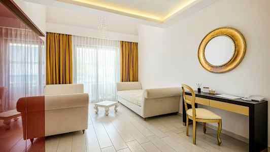 Billede af et lyst værelse med to sofaer, et lille bord, et guldfarvet spejl og skrivebord med stol. (AI-genereret tekst)