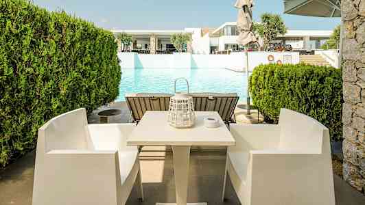 Bord og stole foran en pool. (AI-genereret tekst)