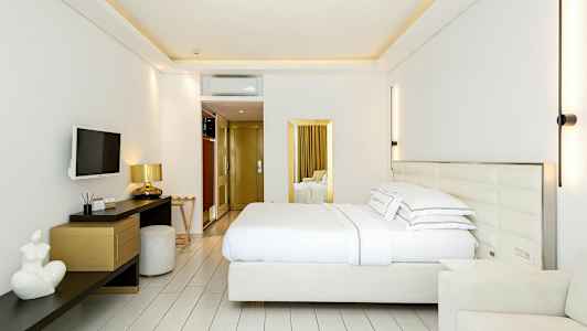 Et moderne hotelværelse med en dobbeltseng, vægmonteret tv, skrivebord og stole. (AI-genereret tekst)