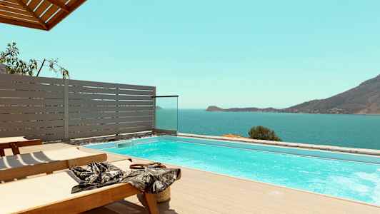 Liggestole ved en pool med udsigt over havet og bjerge. (AI-genereret tekst)