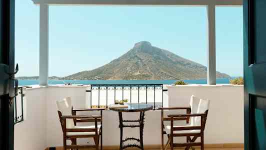 Veranda med to stole og et bord, udsigt over havet og bjerge. (AI-genereret tekst)