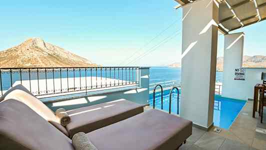 To solsenge ved en lille pool med havet og bjerglandskab i baggrunden. (AI-genereret tekst)