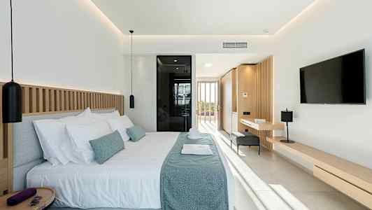 Moderne hotelværelse med dobbeltseng, vindue i baggrunden og lyse nuancer i indretningen. (AI-genereret tekst)