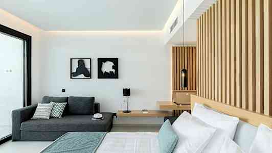 Et moderne hotelværelse med en seng, en sofa og en væg med træpaneler. (AI-genereret tekst)