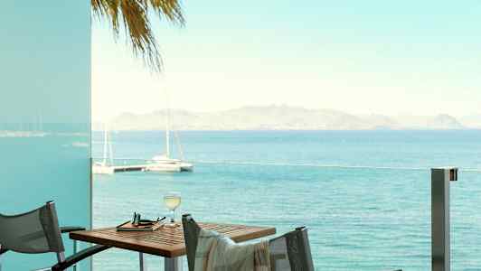 Udsigt over havet fra en altan med bord og stole. (AI-genereret tekst)