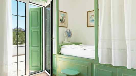 Et værelse med grønne møbler og en dør, der fører til en altan. (AI-genereret tekst)