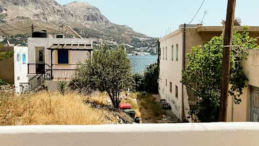 Udsigt over huse og terrasser med bjerge og hav i baggrunden. (AI-genereret tekst)