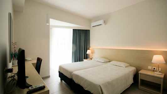 Hotelværelse med to enkeltsenge, skrivebord med tv og lampe på natbordet. (AI-genereret tekst)