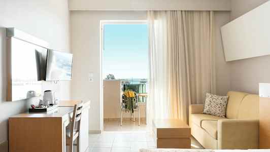 Hotelværelse med altan, TV, skrivebord, sofa og seng. (AI-genereret tekst)