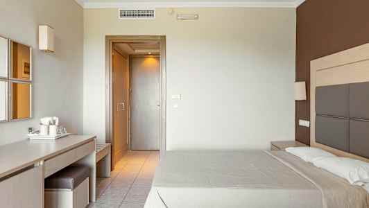 Hotelværelse med en dobbeltseng, et skrivebord med stol og spejl samt en dør til øvrige områder. (AI-genereret tekst)