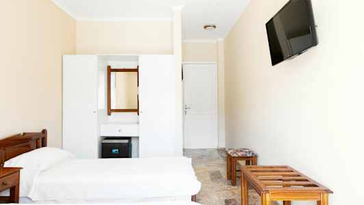 Et hotelværelseinteriør med to enkeltsenge, en kommode med spejl og et vægmonteret TV. (AI-genereret tekst)