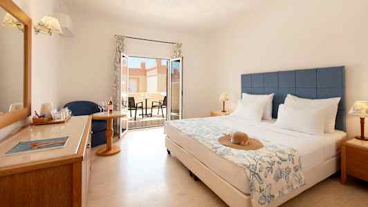 Hotelværelse med dobbeltseng, siddeområde, vindue og møbleret terrasse. (AI-genereret tekst)