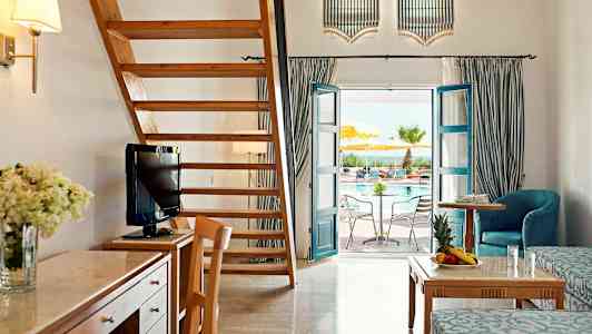 Et rummeligt hotelværelse med trømøbler, en trætrappe og en dør, der fører ud til en pool. (AI-genereret tekst)