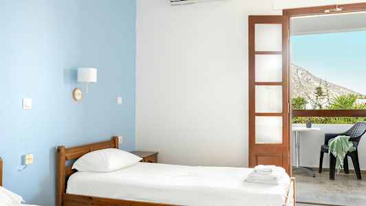 Et hotelværelse med to enkeltsenge og en balkon med udsigt. (AI-genereret tekst)