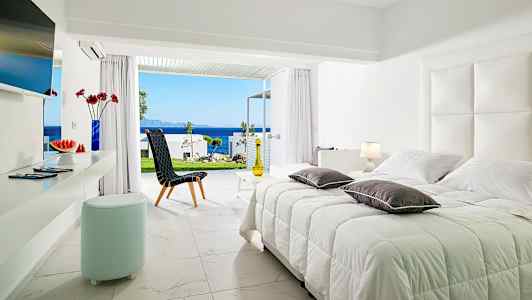 Lyst soveværelsesinteriør med udsigt over havet gennem åbne glasdøre. (AI-genereret tekst)