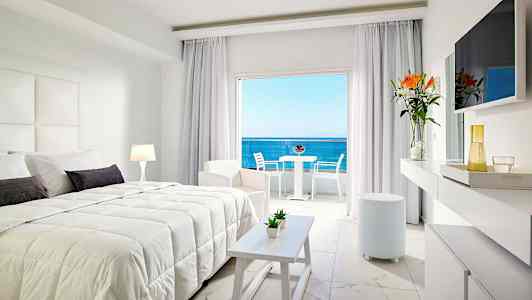 Moderne hotelværelse med dobbeltseng, lyse møbler og udsigt over havet. (AI-genereret tekst)