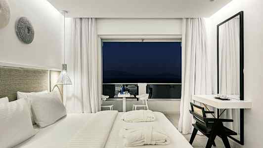 Moderne hotelværelse med stor seng og udgang til altan. (AI-genereret tekst)