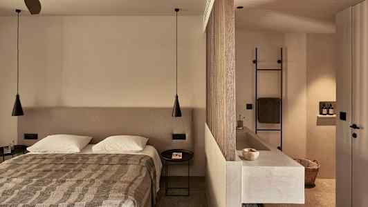 Et soveværelse med en dobbeltseng, en rumdeler der adskiller et badeværelse med håndvask og håndklædeholder. (AI-genereret tekst)