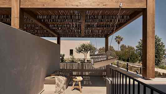 En udendørs terrasse med en træpergola, en hængekøje og et siddeområde med bord. (AI-genereret tekst)