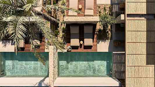 Set ovenfra: solsenge og to swimmingpools med en palme ved siden af. (AI-genereret tekst)