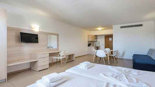 Et hotelværelse med seng, skrivebord, tv og spiseplads med køkkenudstyr. (AI-genereret tekst)