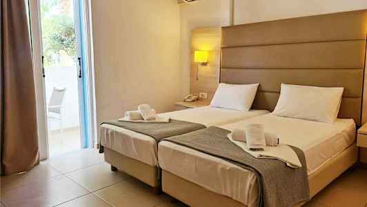 Hotelværelse med to enkeltsenge, natbord og et klimaanlæg på væggen. (AI-genereret tekst)