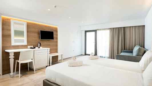 Et hotelværelse med to senge, et skrivebord, TV og siddegruppe. (AI-genereret tekst)