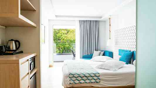 Billede af et lyst hotelværelse med seng, sofa og vindue med udsigt. (AI-genereret tekst)