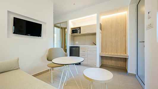 Et moderne hotelværelse med en lille siddegruppe og køkkenområde. (AI-genereret tekst)